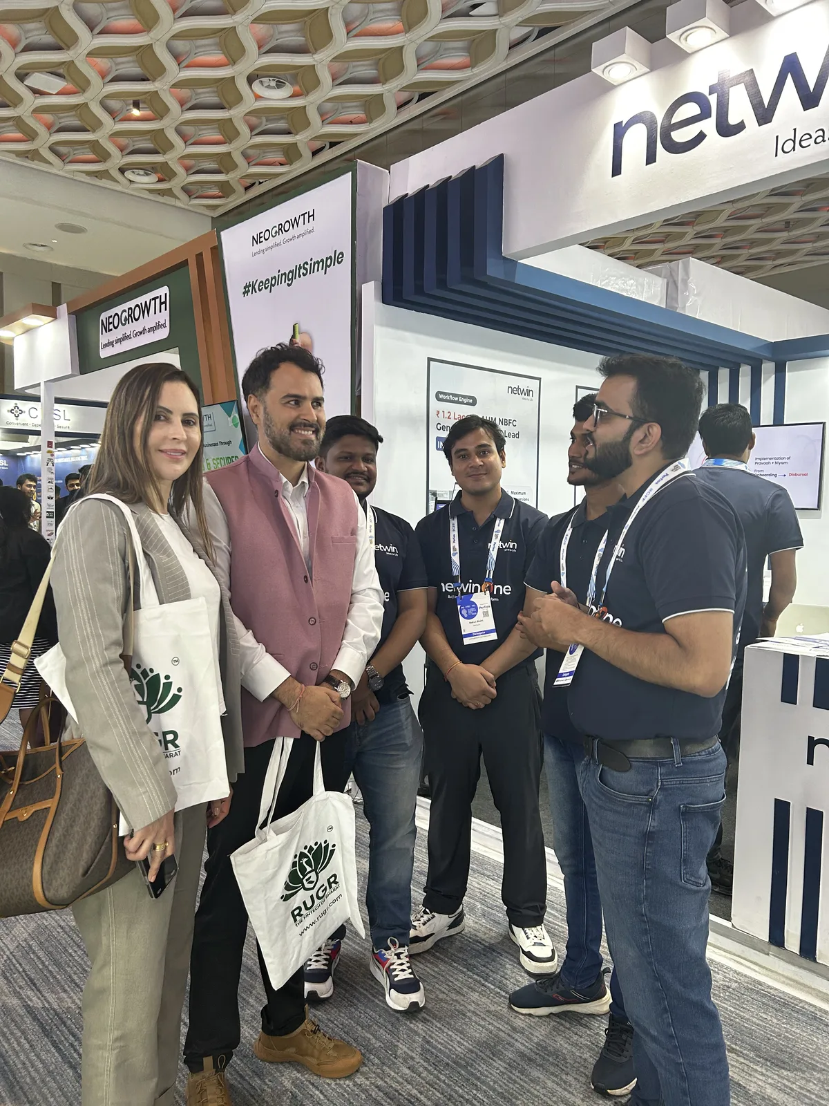 Visitors posing with the Netwin team in front of the booth signage