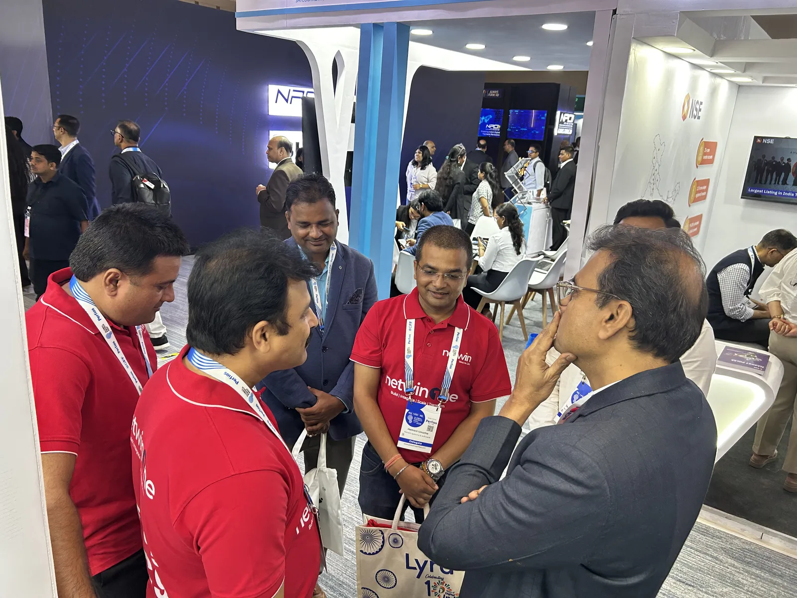 Netwin team in red branded polos greeting visitors at the booth